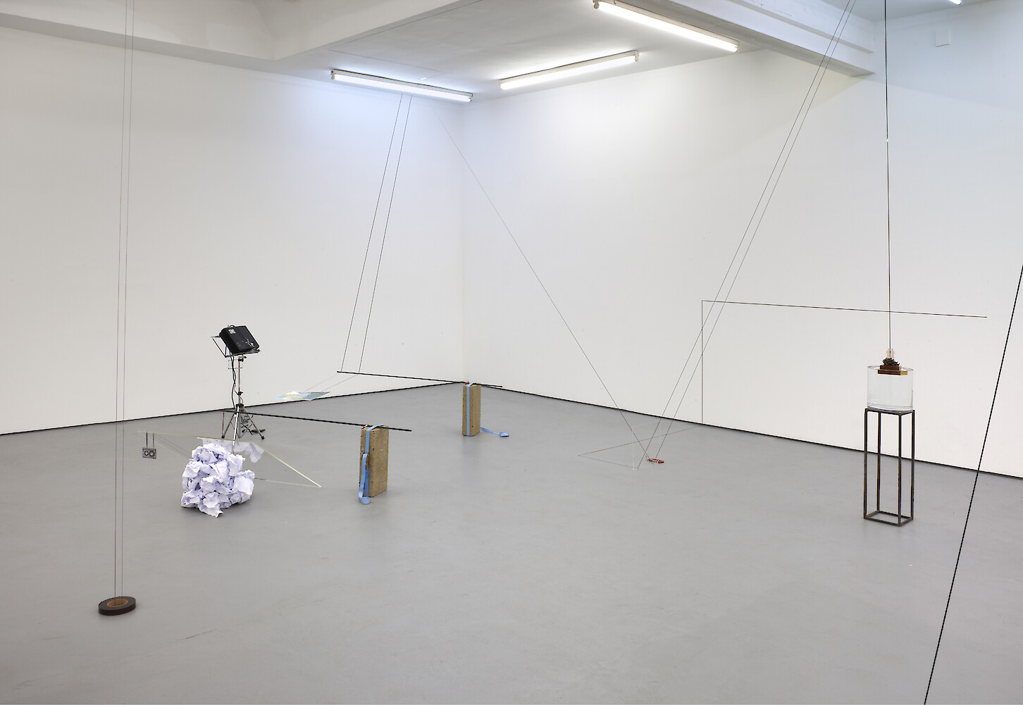 Chooc Ly Tan, *It Depends Mostly On the Slant Of Interplanetary Magnetic Field Lines*, 2012, Mixed media installation with cassette tape, music stand, video projector, water, Plexiglass, two fluorescent lights